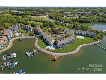 Stunning aerial view of lakeside condos with mature trees, boat docks, and lovely green spaces at 1211 Torrence Cir, Davidson, NC 28036