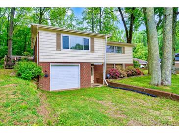 Split-level home features a front-entry garage, mature trees, and colorful shrubs enhancing the curb appeal at 1409 Sherwood Dr, Kannapolis, NC 28081