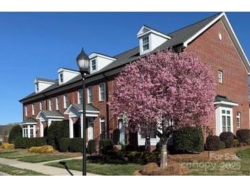 Charming brick townhome featuring a blooming tree and well-maintained landscaping at 216 Harrison Ln # 4, Locust, NC 28097