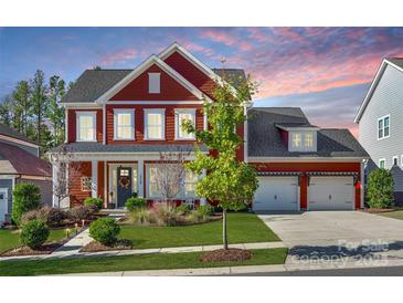 Charming two-story home with red siding, a three-car garage, and a beautifully landscaped front yard at 2329 Paddlers Cove Dr, Clover, SC 29710