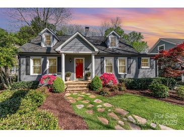 Charming gray brick home with a red door, dormer windows, and beautifully landscaped front yard with a stone walkway at 2909 Park Rd, Charlotte, NC 28209