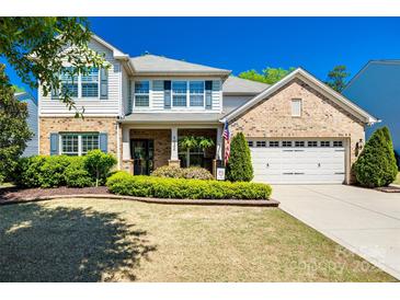 Charming two-story home featuring brick and vinyl siding, lush landscaping, and a welcoming two-car garage at 4032 Wild Turkey Ln, Indian Land, SC 29707