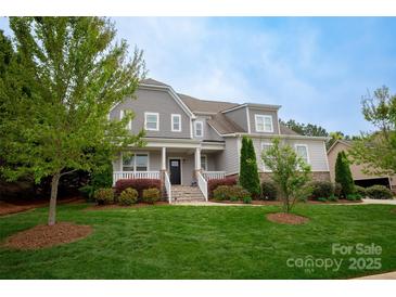 Charming two-story home with manicured lawn, gray siding, stone accents and welcoming front porch at 4205 Green Park Ct, Harrisburg, NC 28075