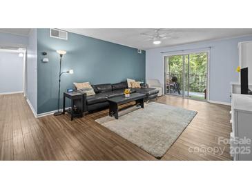 Inviting living room featuring a plush black leather sectional sofa and sliding glass doors to the patio at 4754 Hedgemore Dr # O, Charlotte, NC 28209