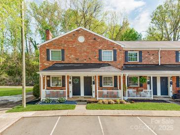 Charming brick townhome featuring a covered front porch and landscaped yard at 1217 Green Oaks Ln # K, Charlotte, NC 28205