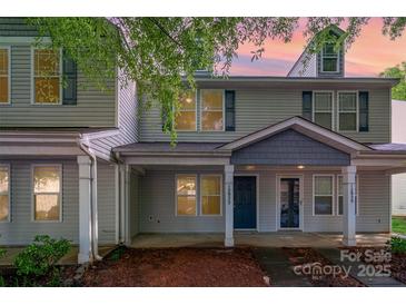 Charming two-story townhome with covered front porch and neutral siding at dusk at 12925 Windy Lea Ln, Huntersville, NC 28078