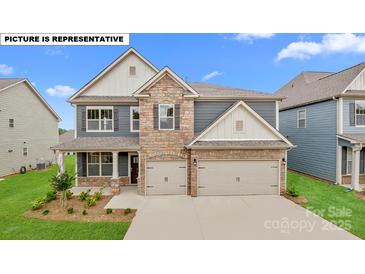 Charming two-story home with stone accents, a manicured lawn, and a two-car garage at 156 Asmodean Ln, Troutman, NC 28166