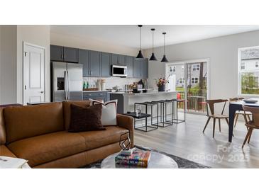 Modern kitchen with gray cabinets, stainless appliances, and a large island with bar seating opening to the living room at 2100 Endeavor Run, Charlotte, NC 28269
