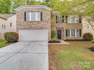 Traditional brick home featuring an attached two-car garage and a well-maintained front lawn at 3227 Deshler Morris Ln, Charlotte, NC 28216