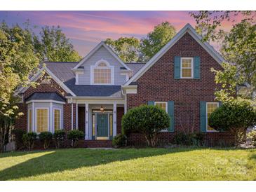 Charming brick home featuring manicured landscaping, a covered porch, and beautiful, colorful sunset at 585 Highland Ridge Rd, Mooresville, NC 28115