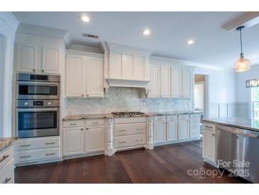 Bright kitchen features stainless steel appliances, white cabinetry, granite counters, and a tile backsplash at 8810 Cool Meadow Dr, Huntersville, NC 28078