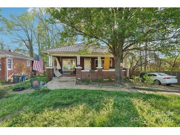 Charming brick home featuring a covered porch, a mature tree, and a well-maintained lawn at 115 E 11Th St, Salisbury, NC 28144