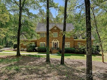 Charming brick two-story home surrounded by mature trees and lush landscaping at 1413 Willow Oaks Trl, Weddington, NC 28104