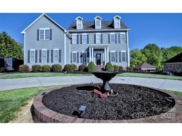 Beautiful two-story home with a manicured lawn, fountain, gray siding, black shutters, and a welcoming entrance at 143 S Gibbs Rd, Mooresville, NC 28117