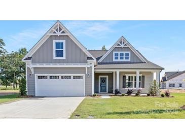Charming home exterior features a well-manicured lawn, a two-car garage and inviting front porch at 908 Cypress Point Ln # 218, Monroe, NC 28112