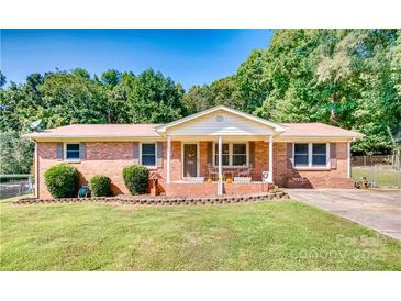 Charming brick ranch home with a well-maintained lawn, front porch, and mature trees at 124 Riley Rd, Dallas, NC 28034