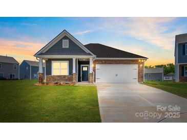 Charming single-story home boasts stone accents, inviting front porch, and well-manicured lawn at 1324 Secrest Commons Dr, Monroe, NC 28112