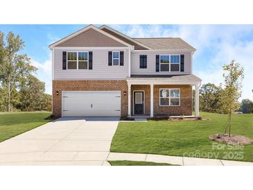 Charming two-story home with brick and siding exterior, a well-manicured lawn, and an attached two-car garage at 1332 Secrest Commons Dr, Monroe, NC 28112