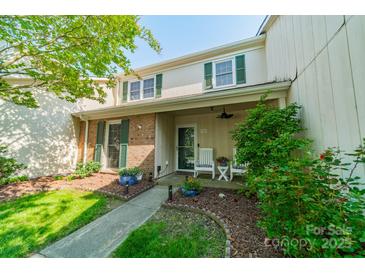 Charming townhome featuring a front porch with white chairs, lush landscaping, and traditional green shutters at 6809 Copernicus Cir, Charlotte, NC 28226