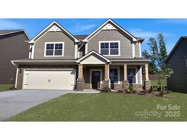 Charming two-story home boasts a stone facade, a well-manicured lawn, and attached two car garage at 7023 Butternut Oak Ter, Huntersville, NC 28078
