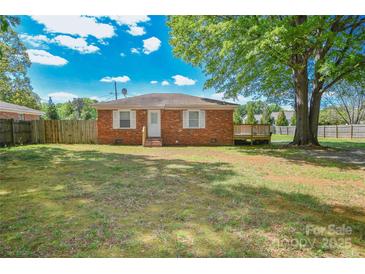 Charming brick home features a well-maintained lawn, fenced yard, and a small wooden deck perfect for enjoying the outdoors at 3203 Valleydale Rd, Monroe, NC 28110