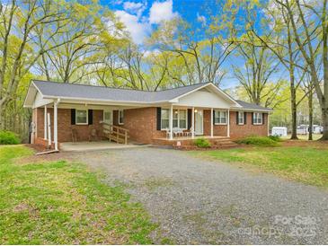 Charming brick ranch home with a carport and a spacious front yard surrounded by mature trees at 322 S Main St, Shelby, NC 28152