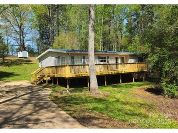 Ranch style home featuring a large front deck, light siding and blue shutters surrounded by mature trees at 3325 Stony Brook Cir, Newton, NC 28658