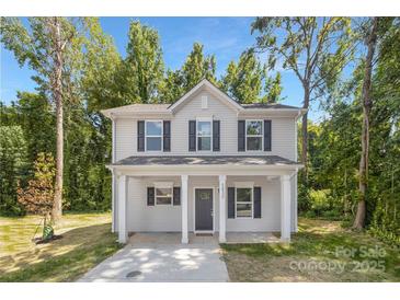 Charming two-story home featuring a covered porch and a well-maintained front yard surrounded by mature trees at 3354 W Sugar Creek Rd, Charlotte, NC 28269