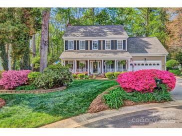 Charming two-story home featuring a welcoming front porch and a beautifully landscaped front yard with vibrant pink flowers at 394 Runnymede Dr, Rock Hill, SC 29732