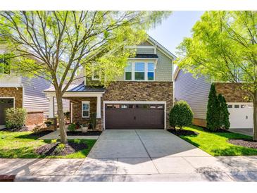 Charming two-story home boasts a stone facade, a two-car garage, and a neatly landscaped front yard with mature trees at 6024 Glenmore Garden Dr, Charlotte, NC 28270
