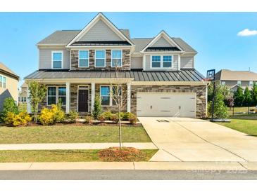 Charming two-story home featuring a stone and siding facade, attached two car garage, and well-manicured lawn at 8008 Hudson Mill Dr, Waxhaw, NC 28173