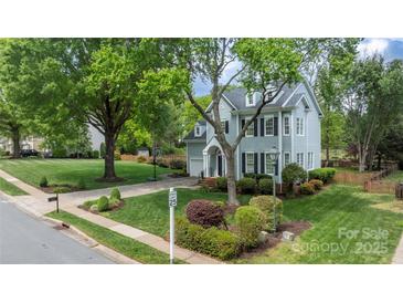Charming two-story home featuring a lush front lawn, mature trees, and classic architectural details at 8517 Sandowne Ln, Huntersville, NC 28078