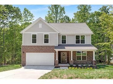 Charming two-story home with a brick facade, attached garage, and a well-manicured front lawn at 8937 Penstemons Dr, Charlotte, NC 28215
