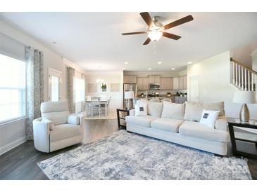 Open-concept living room featuring hardwood floors and neutral tones connects to kitchen and dining area at 221 Mountain Island Dr, Statesville, NC 28677