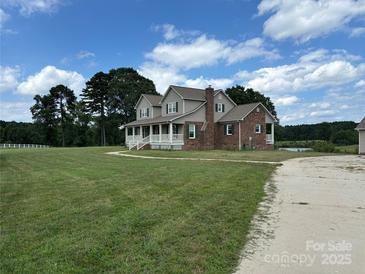 Charming two-story home with a brick chimney, covered porch, and lush green lawn at 2417 Lynwood Dr, Lancaster, SC 29720