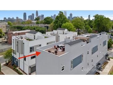 An aerial view of the modern townhome exteriors with a rooftop patio and the Charlotte skyline in the background at 310 Wesley Heights Way, Charlotte, NC 28208
