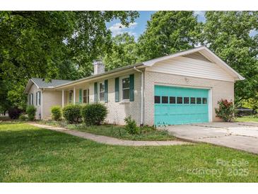 Charming white brick home with green shutters and a brightly colored turquoise garage door at 334 Hudson Dr, Harrisburg, NC 28075