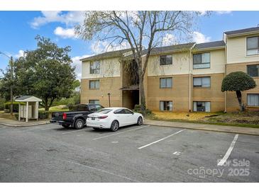 Brick apartment building with tan siding, mature landscaping, and ample parking spaces for residents and guests at 4816 Spring Lake Dr # B, Charlotte, NC 28212