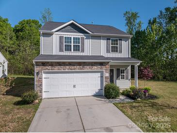 Charming two-story home with stone accents, vinyl siding, a white garage door and well-manicured front yard at 9112 Avery Meadows Dr, Charlotte, NC 28216