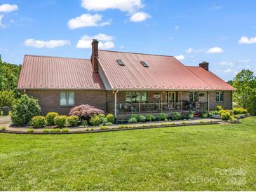 Charming brick home with a red metal roof, covered porch, and well-manicured lawn at 2251 Old Applewood Ln # 9, Iron Station, NC 28080