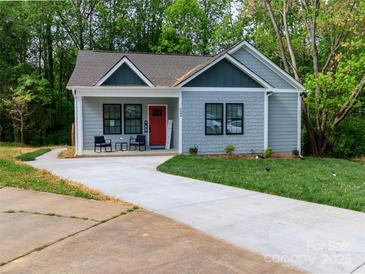 Charming home featuring a well-manicured lawn, inviting front porch, and a vibrant red front door at 2302 Jordi Way, Charlotte, NC 28213