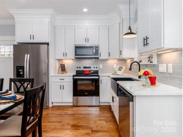 Bright kitchen features stainless steel appliances, white cabinetry, subway tile backsplash, and hardwood flooring at 2302 Jordi Way, Charlotte, NC 28213
