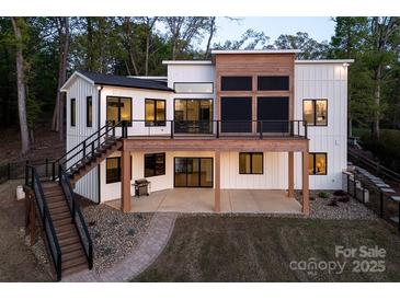 Modern home featuring a deck, white siding, black trim, outdoor stairs and a stone path at 264 Fairway Shores Rd, Mount Gilead, NC 27306