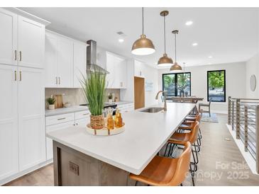 Modern kitchen features a large island, white cabinets, stainless steel appliances, and beautiful pendant lighting at 3449 Byrnes St, Charlotte, NC 28205