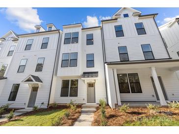 Eye-level exterior shows the front of a three-story modern white townhome with black window trim and a covered porch at 655 District Ct, Fort Mill, SC 29708