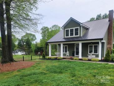 Charming home showcasing a landscaped yard and inviting front porch with classic columns and cozy rocking chairs at 788 N Main St, Mount Pleasant, NC 28124