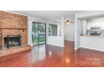 Bright living room featuring hardwood floors and sliding glass door to balcony with view to kitchen at 10967 Harrowfield Rd, Charlotte, NC 28226