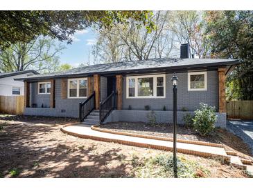 Charming gray brick home featuring a welcoming front porch and well-maintained landscaping at 2014 Sandhurst Dr, Charlotte, NC 28205