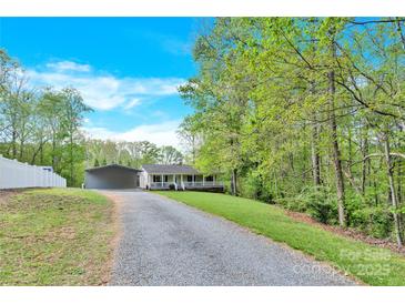 Inviting home with charming front porch, gravel driveway, and spacious carport nestled among lush trees at 2315 Collins Dr, Albemarle, NC 28001