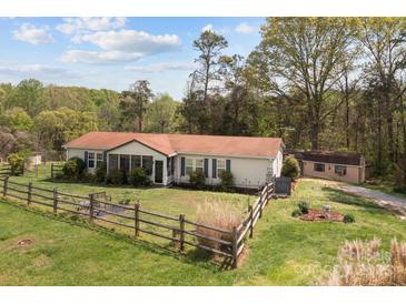 Charming single-story home features a fenced yard, screened porch and a cozy outdoor fire pit area at 335 Ridgewood Dr, Mt Ulla, NC 28125